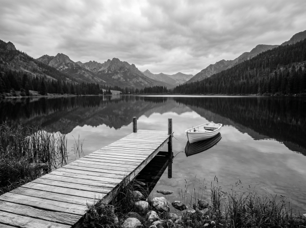 Wooden dock and rowboat on a mountain lake at sunset